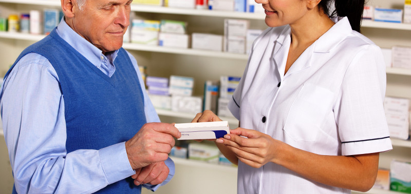 American pharmacist serving  senior man in pharmacy